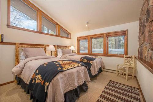 two beds in a bedroom with two windows at Bray House - Ski-in Ski-out family home in Teton Village