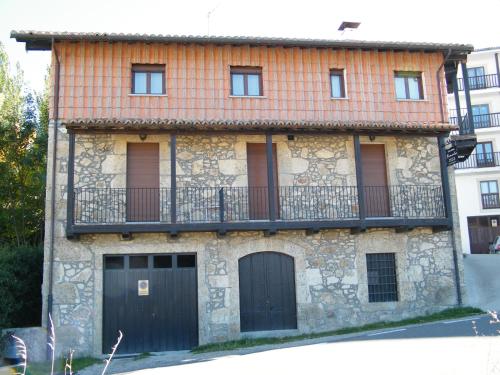 Edificio de piedra con balcón y 2 puertas en Casa Rural Puerta del Sol de 3 habitaciones en Candelario