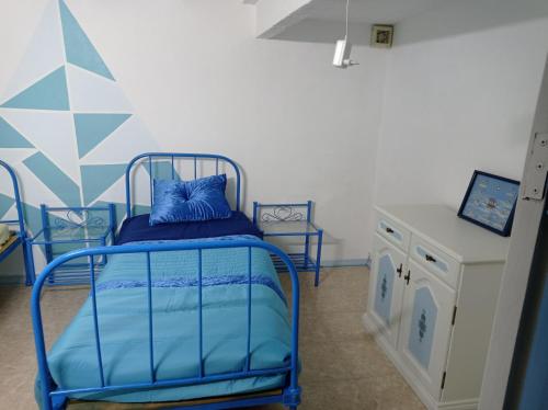 a small bedroom with a blue bed and a table at La maison du bonheur in Celavisa