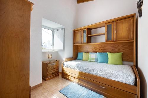 1 dormitorio con 1 cama con cabecero de madera y ventana en Refúgio dos Pais, en Bordeira