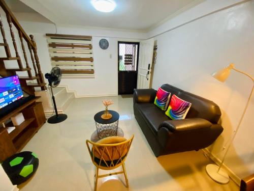 Gillera Staycation in Lipa في ليبا: غرفة معيشة مع أريكة جلدية وتلفزيون