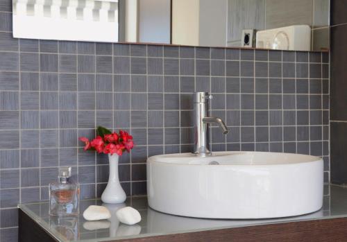 a bathroom counter with a sink and a vase of flowers at Sivota Senses - Villa Loukas in Sivota