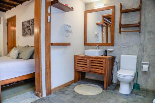a bathroom with a sink and a toilet and a bed at Tranquilisle in Kandy