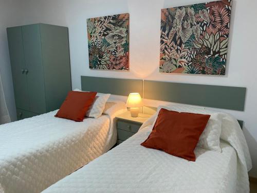 a bedroom with two beds and a lamp on a table at Apartamentos Alcañiz, Silvia in Alcañiz