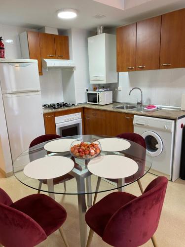 eine Küche mit einem Glastisch mit Stühlen und einer Obstschale in der Unterkunft Apartamentos Alcañiz, Silvia in Alcañiz