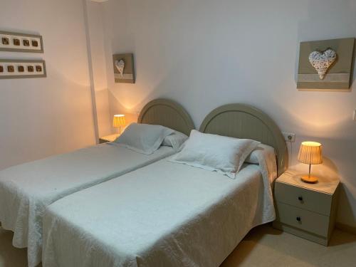 a bedroom with two beds and a table with a lamp at Apartamentos Alcañiz, Silvia in Alcañiz