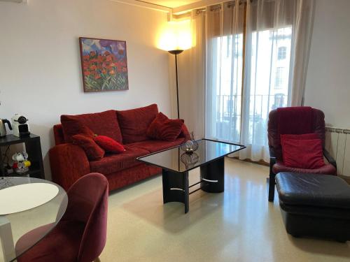 a living room with a red couch and two chairs at Apartamentos Alcañiz, Silvia in Alcañiz