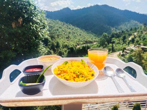 een tafel met kommen eten en een glas sinaasappelsap bij Aranya Mukteshwar in Mukteswar