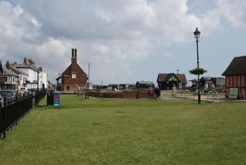 a park with a fence and houses and a street at Tirah Guest House in Aldeburgh