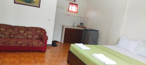 a living room with a couch and a bed at ALTHEA BIRDS NEST INN in Moalboal