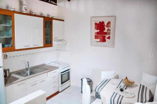 eine Küche mit weißen Schränken, einer Spüle und einem Tisch in der Unterkunft Pagiantes in Agios Nikolaos