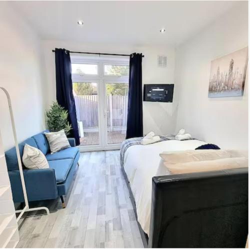 a bedroom with a bed and a blue couch and a window at Studio Rooms Ensuite Newbury Park London in Seven Kings
