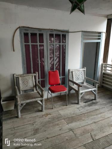 due sedie e una sedia rossa su un portico di CHEAPEST Bungalow AC ROOM a Sabang