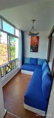 - un salon avec un canapé bleu et une fenêtre dans l'établissement Appartement de vacances piscine et plage de Cabo Negro, à Cabo Negro