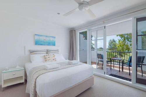 Villa Aqua 6 - Riverfront Noosaville في نوسافيل: غرفة نوم بيضاء مع سرير وشرفة