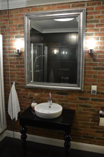 a bathroom with a sink and a mirror on a brick wall at Apartamenty Adalbert in Gdańsk