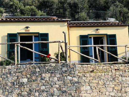 a house with green windows and a stone wall at Eufonia del Mare in Finale Ligure