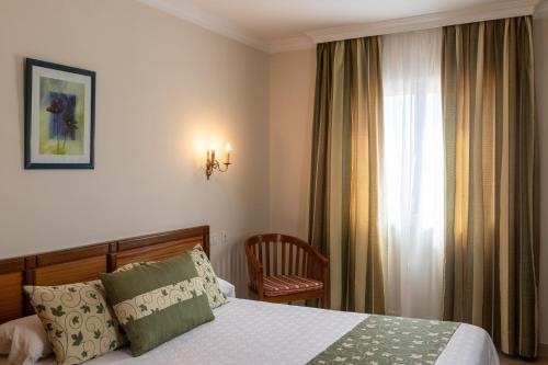 a bedroom with a bed and a window and a chair at Hotel Marte in Puerto de la Cruz
