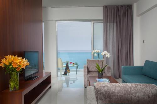 a living room with a blue couch and a tv at King Evelthon Beach Hotel & Resort in Paphos City