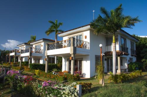 a large white house with palm trees and flowers at Bahia Del Sol Villas & Condominiums in San Juan del Sur