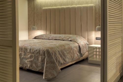 a bedroom with a bed with a large headboard at Caravia Beach Hotel in Marmari