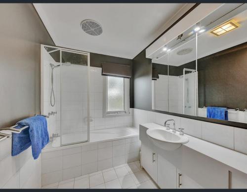 a white bathroom with a sink and a shower at Golf Views Apartment in Mulwala