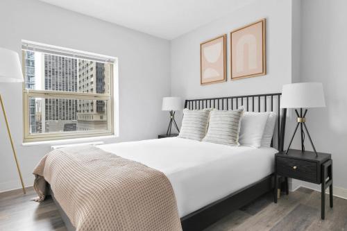 a white bedroom with a large bed and a window at Gold Coast 1BR w Deck Gym Lounge 1 block to L CHI-650 in Chicago