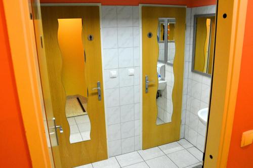 La salle de bains est pourvue de murs et de miroirs jaune et orange. dans l'établissement TEJ HOSTEL, à Ljubljana