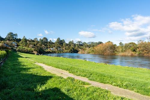 a grassy field next to a river at Riverside in Taupo