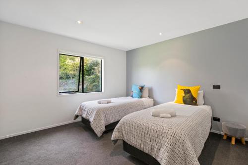 twee bedden in een kamer met witte muren en een raam bij Riverside in Taupo
