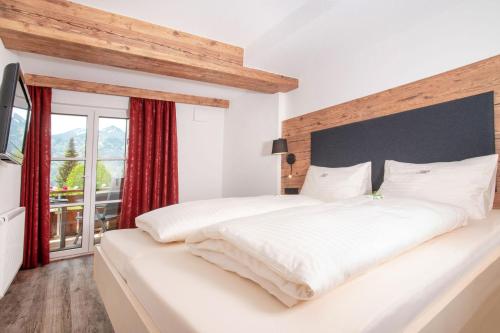 a bedroom with a large white bed with a large window at Landhaus Dodel in Oberstdorf