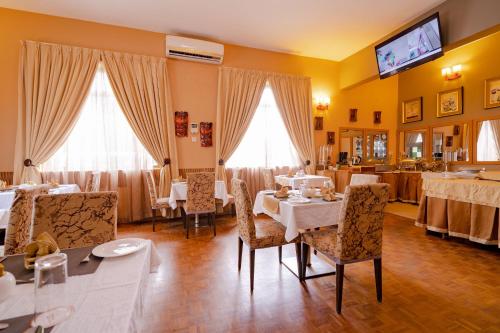 a restaurant with tables and chairs and a tv on the wall at The Amariah Hotel & Apartments Mikocheni in Dar es Salaam