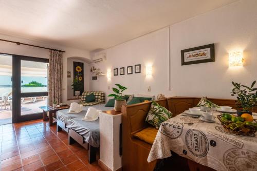 ein Wohnzimmer mit einem Tisch und einem Sofa in der Unterkunft Sun Deck Studio Albufeira Jardim in Albufeira