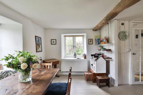 a living room with a wooden table and a vase of flowers at Mount Pleasant Cottage Painswick in Stroud