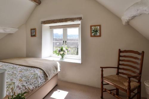 a bedroom with a bed and a chair and a window at Mount Pleasant Cottage Painswick in Stroud