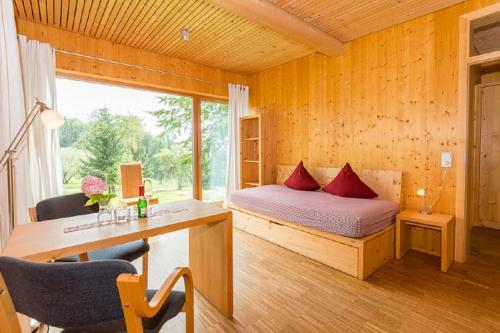 Schlafzimmer mit einem Bett, einem Schreibtisch und einem Fenster in der Unterkunft GutsAlm Harlachberg in Bodenmais