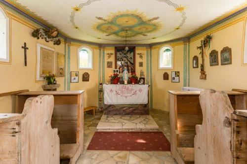 an altar in a church with a cross on the ceiling at GutsAlm Harlachberg in Bodenmais