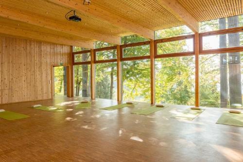 an empty room with yoga mats in a room with windows at GutsAlm Harlachberg in Bodenmais