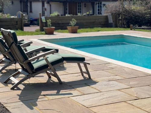 duas cadeiras de jardim sentadas ao lado de uma piscina em The Honeypot at Newlands in Bury em Bury