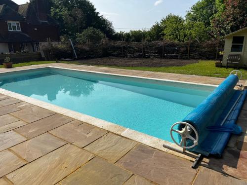 a swimming pool with a blue hose in a yard at The Honeypot at Newlands in Bury in Bury