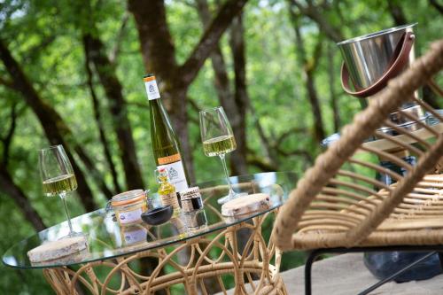 a glass table with a bottle of wine and glasses at La Perle de Domme in Sarlat-la-Canéda