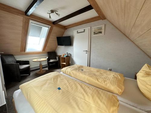 a room with two beds and a living room at Hotel Peters Schwalbennest in Neuharlingersiel