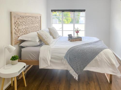a bedroom with a large white bed and a window at Stay on Main, Family Apartment in Paarl