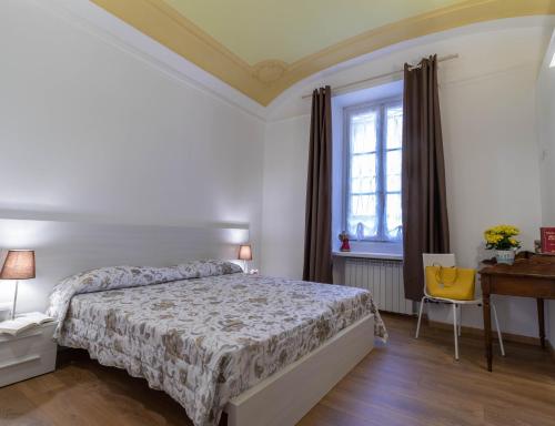 a bedroom with a bed and a desk and a window at Le Montagne - Le Casette di Osvaldo in Lecco