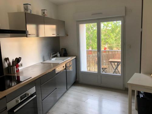 une cuisine avec un évier et une porte coulissante en verre dans l'établissement Bel appartement proche chateau Laurens, à Agde