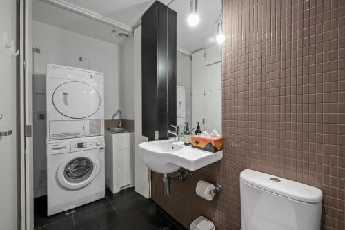 a bathroom with a washing machine and a sink at Exclusive Stays - Seven Yarra in Melbourne