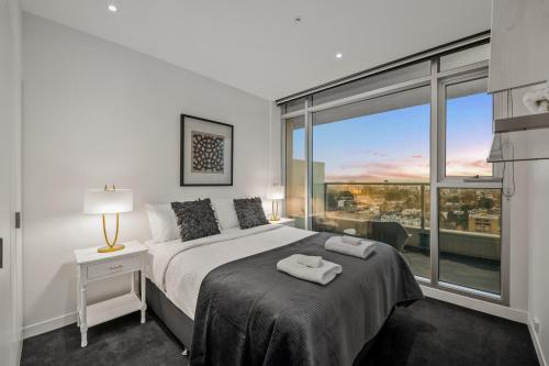 a bedroom with a bed and a large window at Exclusive Stays - Seven Yarra in Melbourne