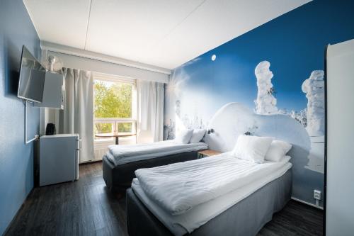 a bedroom with two beds and a blue wall at Hotelli Uninen Loviisa in Loviisa