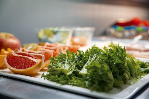 a plate of vegetables and fruit on a table at Hotelli Uninen Loviisa in Lovisa