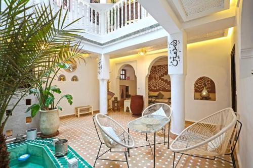a living room with chairs and a table and a plant at Riad Dar El Khir en centre ville rooftop et bassin in Marrakech